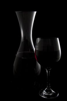 Outlines of wine carafe and wine glass with red wine on black background.