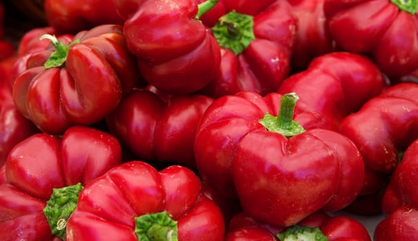 Pile of red pumpkin shaped red peppers at a farmers market