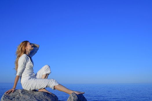 Relaxed young woman enjoying beautiful sunset by the sea.