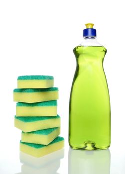 Bottle of green dishwashing liquid and sponges on white background.