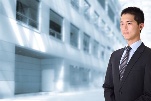 Asian young business man standing and looking in front of office buildings.