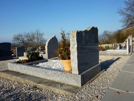 Tomb made of grey marble with flowers in a cemetery