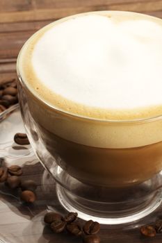 cappuccino on a glass plate in a glass cup on wooden background