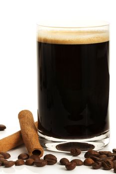 espresso in a straight glass with coffee beans and cinnamon sticks on white background