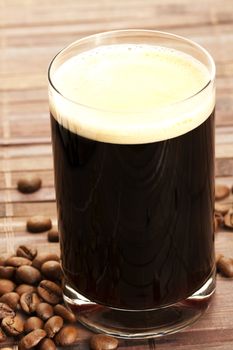 espresso in a glass with coffee beans on wooden background