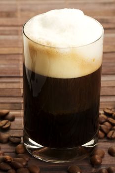 espresso with milk froth and coffee beans on wooden background