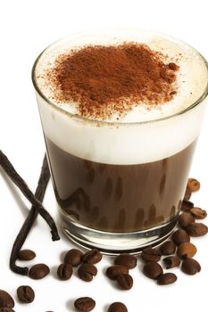 espresso coffee in a short glass with milk froth chocolate powder coffee beans and vanilla beans on white background
