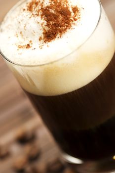soft focus on milk froth of an espresso coffee with cocoa powder on wooden background with coffee beans