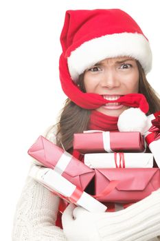 Christmas shopping woman stress. Young shopper holding christmas gifts / presents stressed, frustrated and angry. Funny image of Asian / caucasian woman biting her santa hat and arms full of gifts. Isolated on white background.