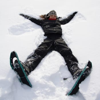 Girl having fun in the snow with snowshoes