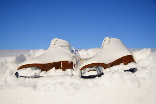 Closeup of figure skating ice skates lying in the snow outdoors
