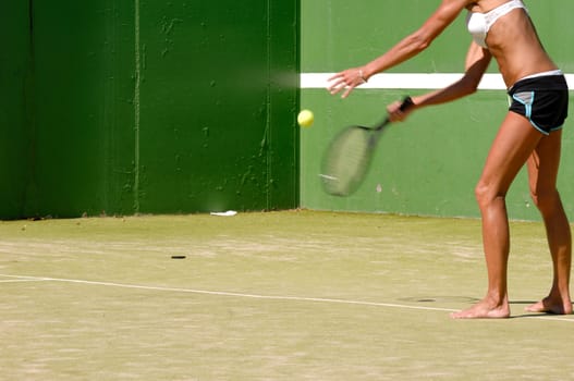 Woman is serving the ball. Note that hand, ball and racket is in motion blur.