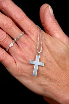 Woman is praying holding her cross. On black clean background.