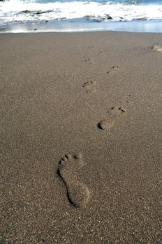 Footprints on the beach leading to the sea.