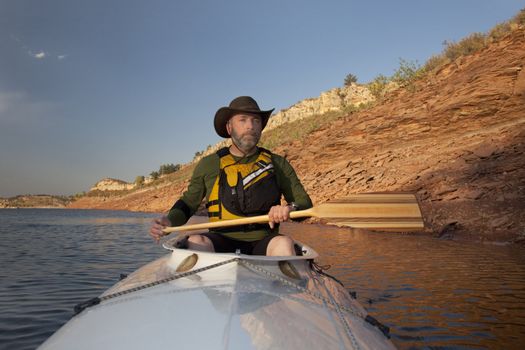 mature adult paddler in an expedition decked canoe on calm mountain lake (Horsetooth Reservoir near Fort Collins, Colorado)