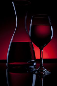Outlines and reflections in carafe of wine and wine glass with red light