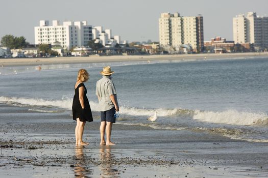 a couple walking on a beach enjoying the view of the ocean