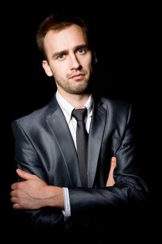 young businessman with arms crossed over black background