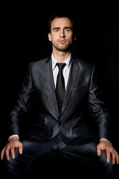 young confident businessman with hands on his knees