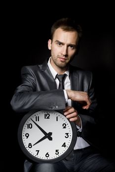 young handsome businessman holding big clock