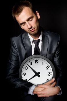 tired sleeping businessman holding clock, over black