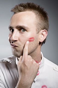 young man pointing on cheek with kiss imprint