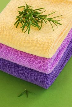 pile of colorful towels with rosemary sprig over green background