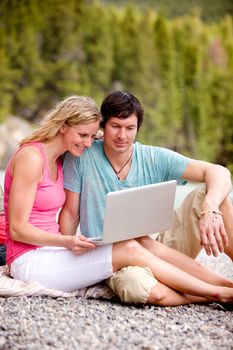 A couple enjoying a laptop computer outdoors