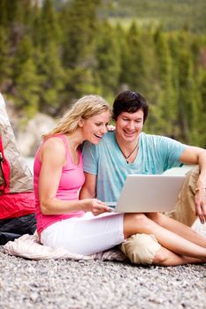 A couple using a laptop while on a camping trip