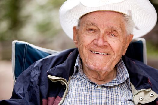 A portrait of a happy smiling elderly man sitting outdoors