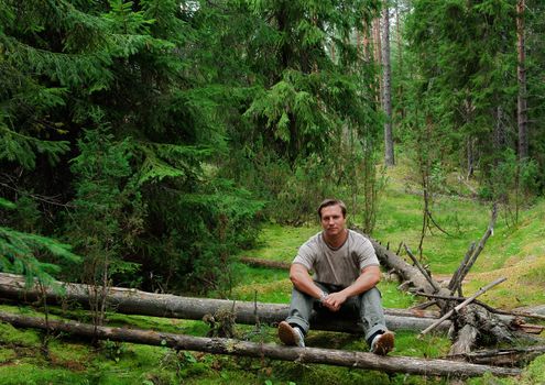 The man in  forest sits on a log