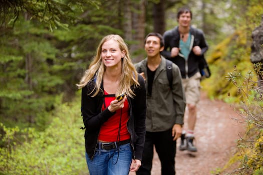 A woman using a GPS in the forest on a camping hike