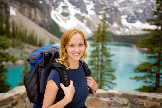 A portrait of a young happy woman infront of a beautiful mountain landscape