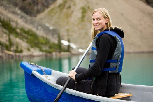 A portrait of a happy woman canoeing on a glacial lake