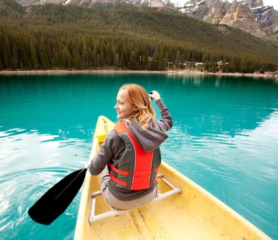 A happy woman in a canoe on a clear glacial lake