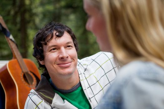 A man smiling at a woman with a guitar in the background