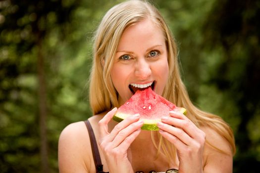 A happy woman eating a fresh watermelon