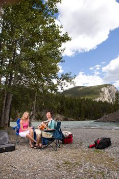 A couple on a camping trip playing the guitar and relaxing
