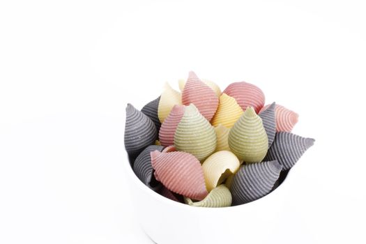 Multicolored pasta shells in small bowl isolated on white