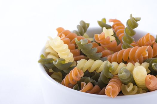 Multicolored fusilli pasta in small white bowl. 