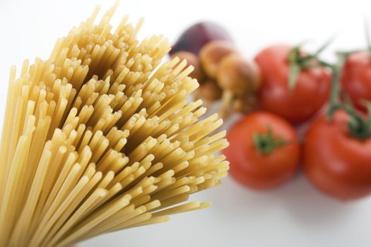 Close up of spaghetti with shallow depth of field.   Tomatoes and mushrooms in distance.