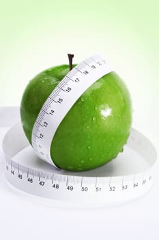 apple with measure tape over fresh green gradient