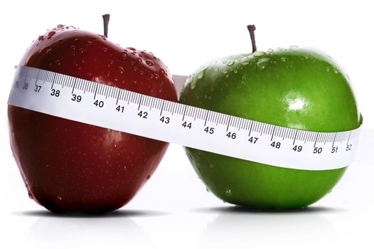 two apples with measure tape over white