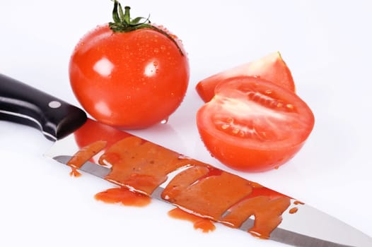 tomatoes and knife stained with ketchup over white