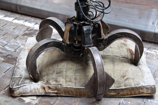 Detail of waste plant: Old mattress with large claw on conveyor belt