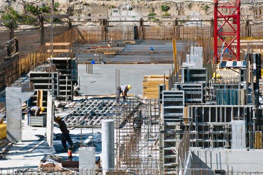 Detail of construction site with workers, scaffolding, crane and assets