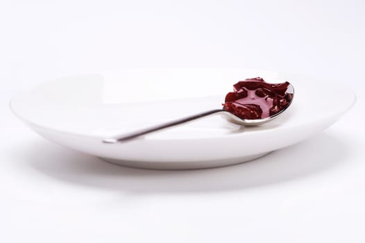 spoon with cherry jam on plate over white background
