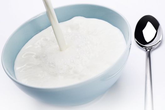 milk poured into a bowl over white background