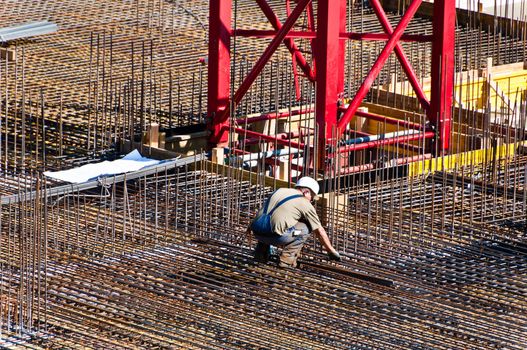 Detail of construction engineer with plan on site with steel and crane