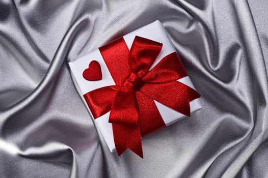 gift with decorative red ribbon on silver background